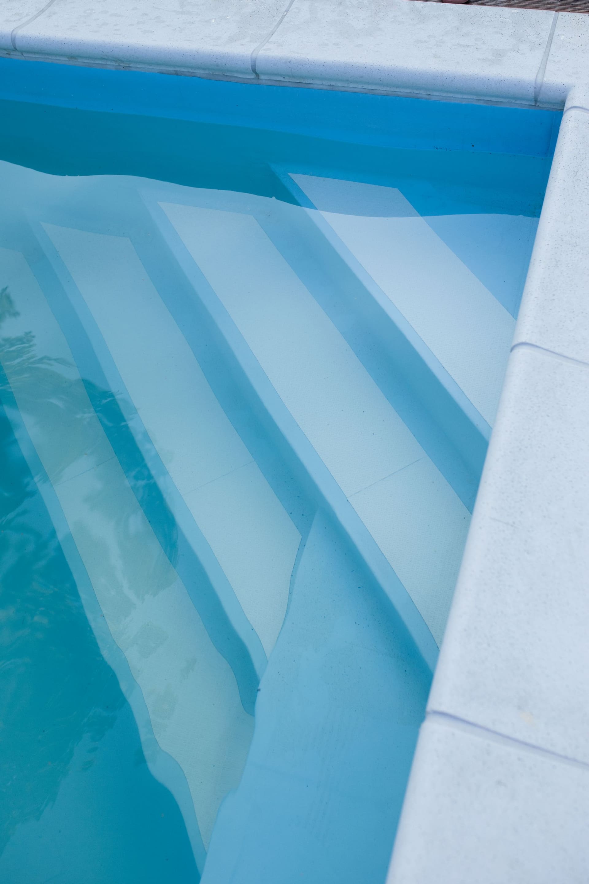 Smooth molded steps leading into clear blue pool water